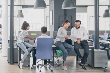 Menschen im B&uuml;ro unter gro&szlig;en Lampenschirmen